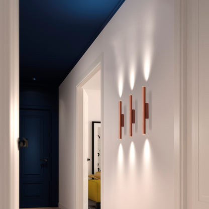 Applique murale LED cylindrique couleur cuivre de la famille Tania, diffusant une lumière chaude et homogène idéale pour un salon ou une chambre moderne.