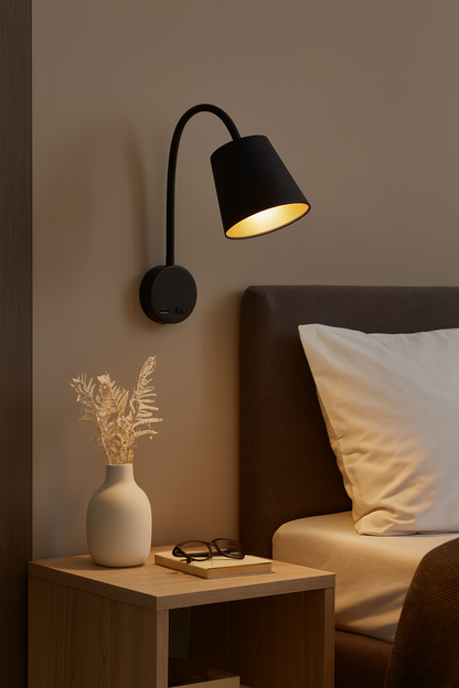 Applique murale noire au design moderne avec intérieur doré, installée près d’un lit. Éclairage doux et chaleureux, idéale pour une chambre contemporaine ou un coin lecture élégant.