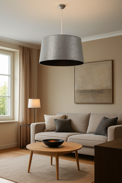 Suspension moderne grise Selma avec abat-jour argenté et intérieur noir, suspendue au-dessus d’un salon contemporain. Éclairage doux et élégant pour espaces résidentiels ou hôteliers.