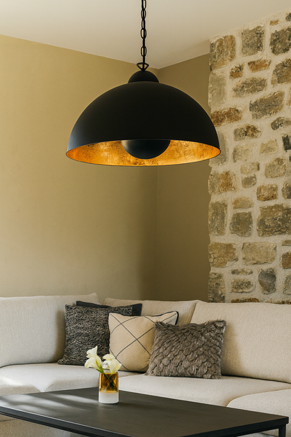Suspension Tanna noire avec intérieur doré, installée dans un salon moderne, au design industriel et chaleureux.